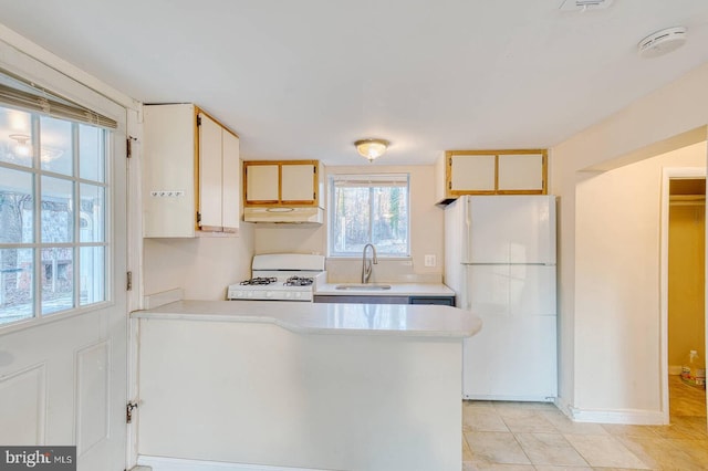 kitchen featuring kitchen peninsula, light tile patterned flooring, white appliances, and sink