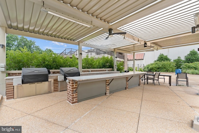 view of patio with an outdoor kitchen, a grill, a pergola, and exterior bar