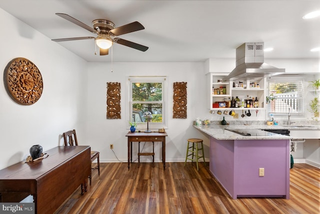 kitchen featuring plenty of natural light, island exhaust hood, light stone counters, and dark hardwood / wood-style flooring