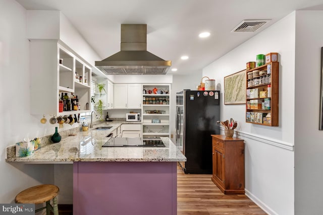 kitchen featuring exhaust hood, kitchen peninsula, sink, black appliances, and light hardwood / wood-style floors