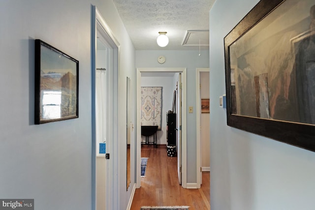 corridor with a textured ceiling and light wood-type flooring