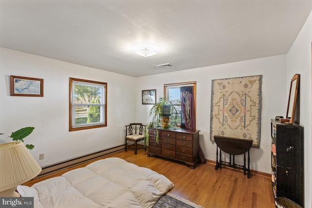 bedroom featuring a baseboard heating unit and light wood-type flooring