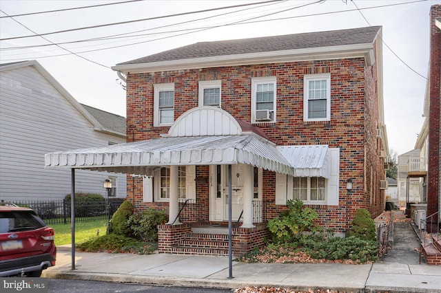 view of front of house featuring covered porch, brick siding, cooling unit, and fence