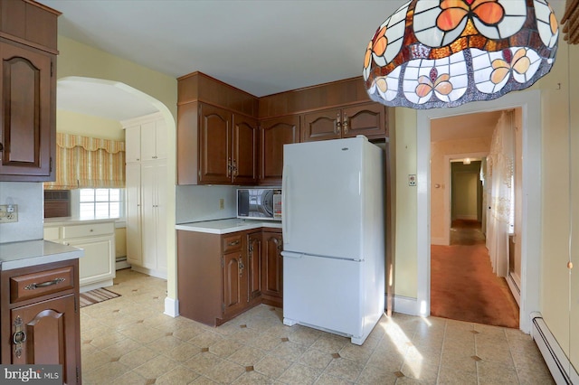 kitchen with a baseboard radiator, arched walkways, light countertops, and freestanding refrigerator