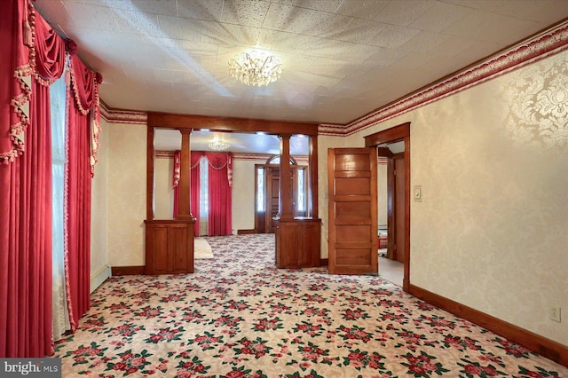 unfurnished room featuring decorative columns, baseboards, and ornamental molding