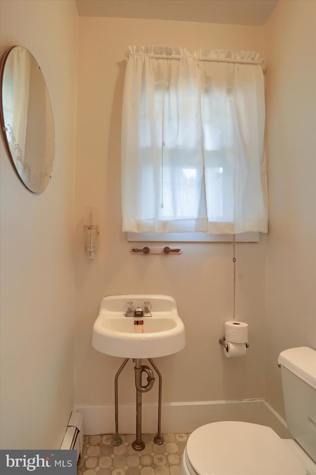 bathroom featuring toilet, a baseboard radiator, baseboards, and a sink