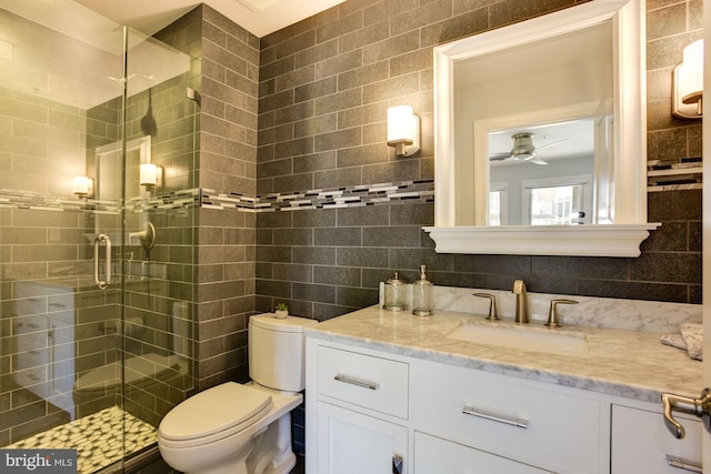 bathroom featuring toilet, walk in shower, vanity, and tile walls