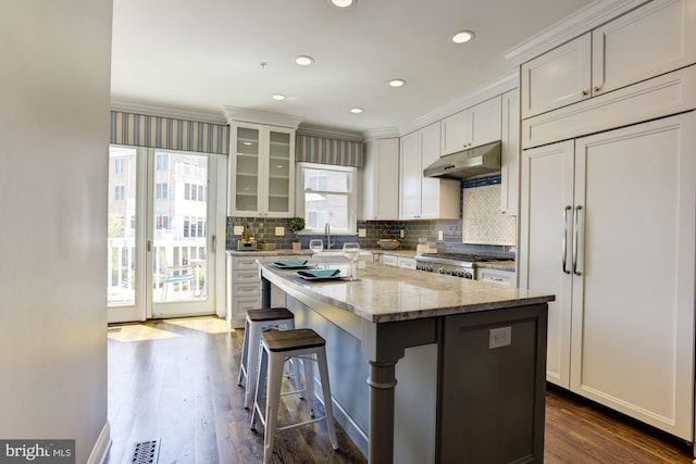 kitchen with dark hardwood / wood-style flooring, light stone countertops, a center island, and paneled built in refrigerator