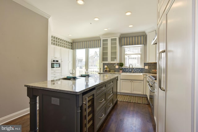 kitchen featuring high quality appliances, backsplash, wine cooler, a center island, and white cabinetry