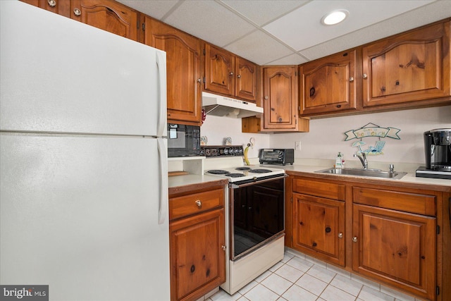 kitchen with sink, light tile patterned flooring, a paneled ceiling, and white appliances