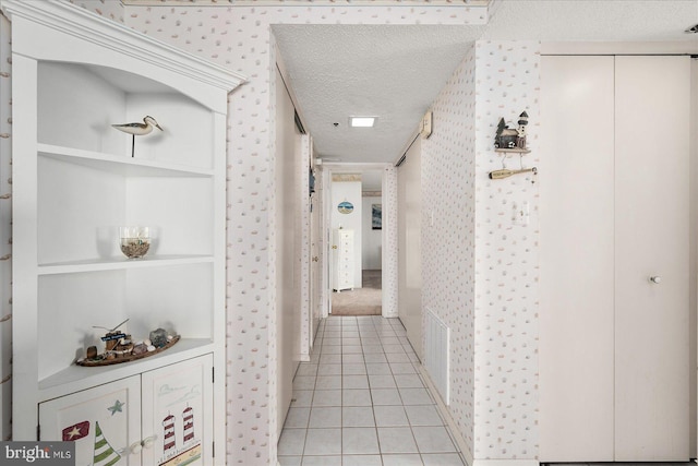 hall with a textured ceiling and light tile patterned flooring