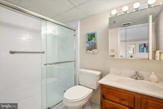 bathroom featuring vanity, a drop ceiling, toilet, and an enclosed shower