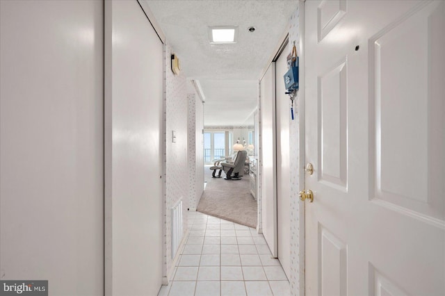 hallway featuring light carpet and a textured ceiling