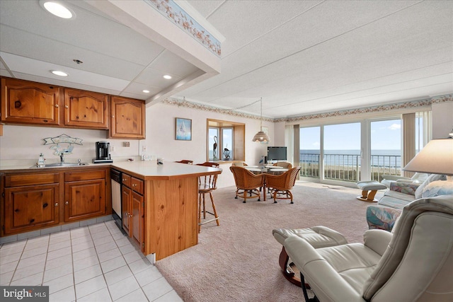 kitchen with a kitchen breakfast bar, kitchen peninsula, dishwashing machine, pendant lighting, and light tile patterned floors