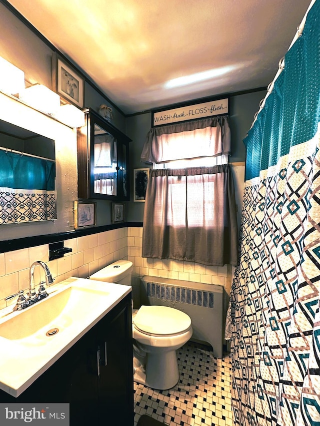 bathroom featuring vanity, toilet, radiator, and tile walls