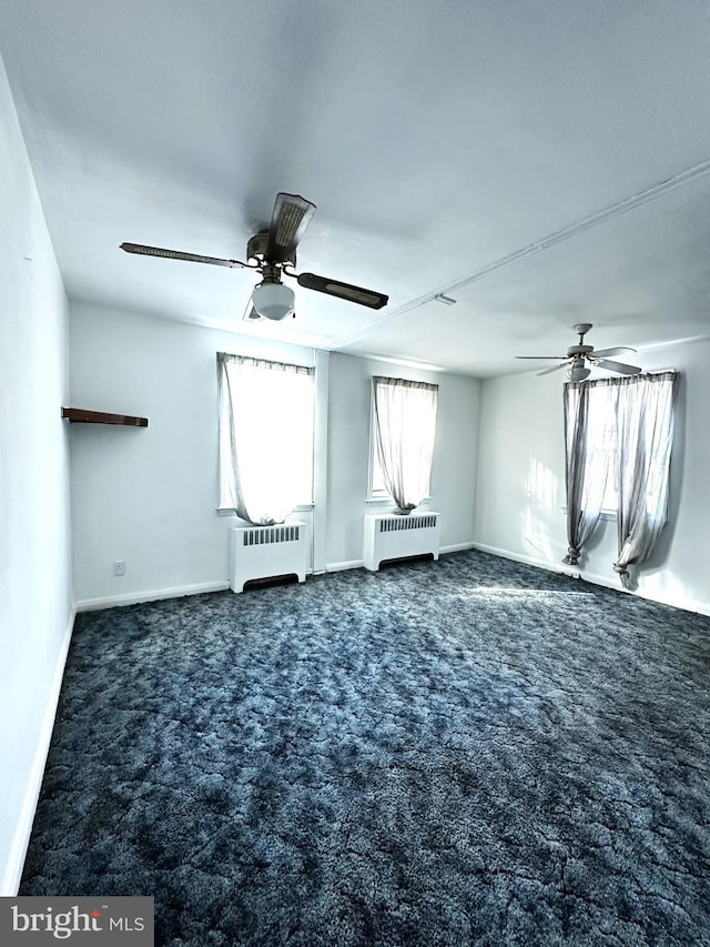 carpeted empty room with radiator and ceiling fan