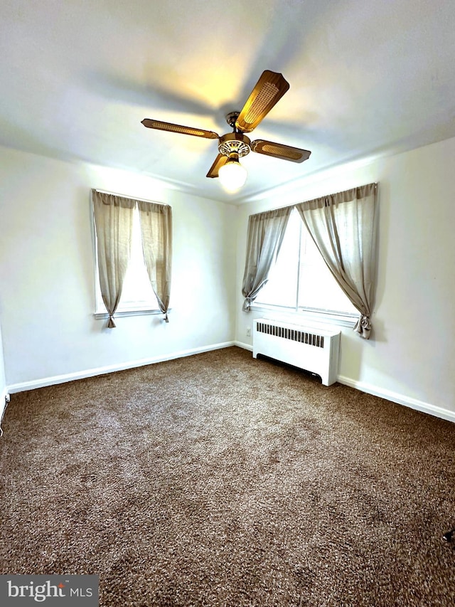 carpeted spare room with radiator and ceiling fan