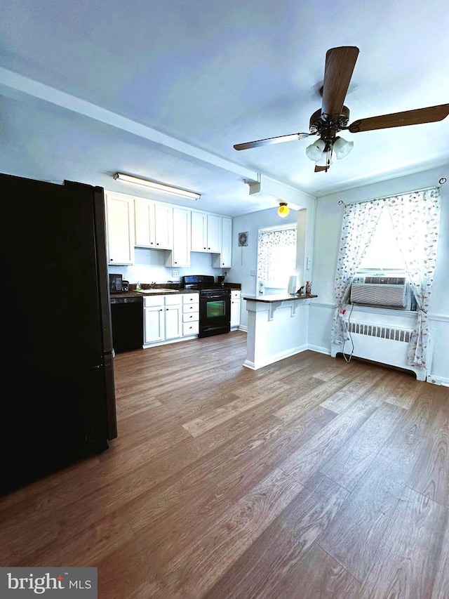 kitchen featuring black appliances, a kitchen breakfast bar, kitchen peninsula, light wood-type flooring, and white cabinetry