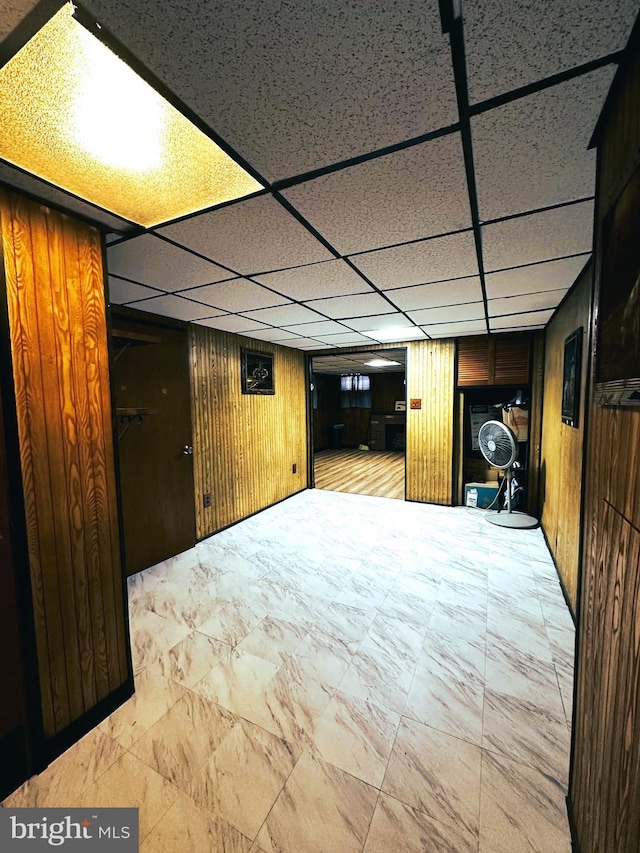 basement with a paneled ceiling and wood walls