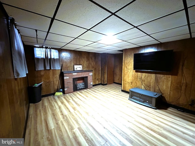 interior space with a fireplace, light wood-type flooring, and wooden walls