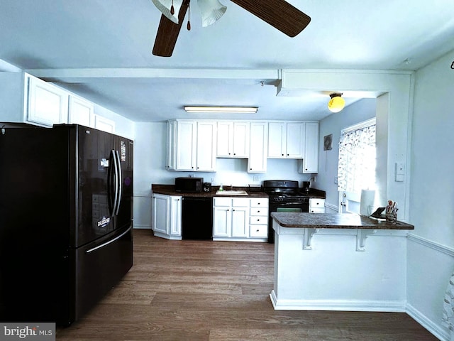 kitchen featuring black appliances, a kitchen bar, white cabinetry, and kitchen peninsula