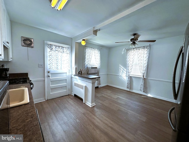 kitchen featuring ceiling fan, dark wood-type flooring, radiator heating unit, white cabinetry, and stainless steel refrigerator