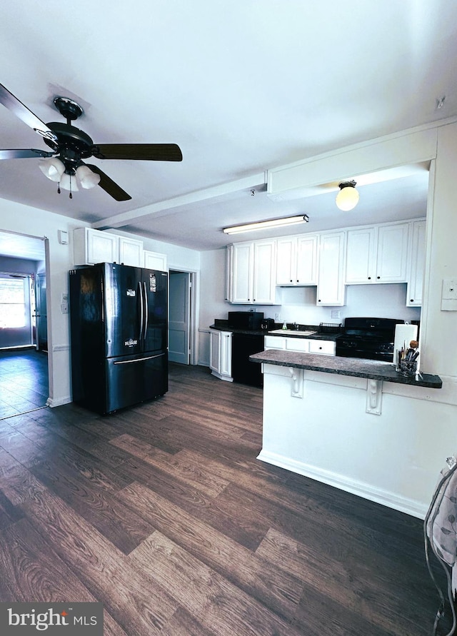 kitchen featuring kitchen peninsula, a kitchen bar, black appliances, dark hardwood / wood-style floors, and white cabinetry