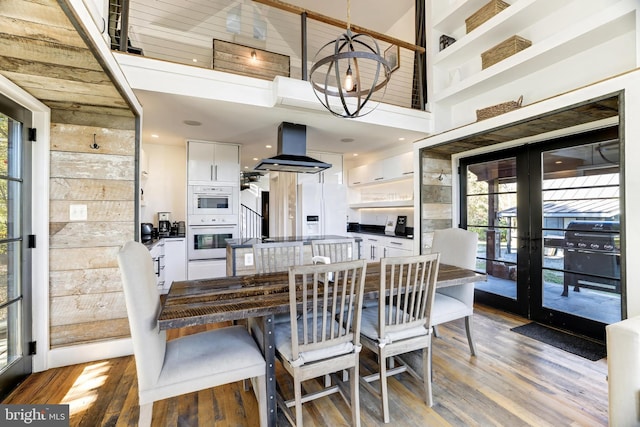 dining area with light wood-style floors, a high ceiling, a chandelier, and french doors