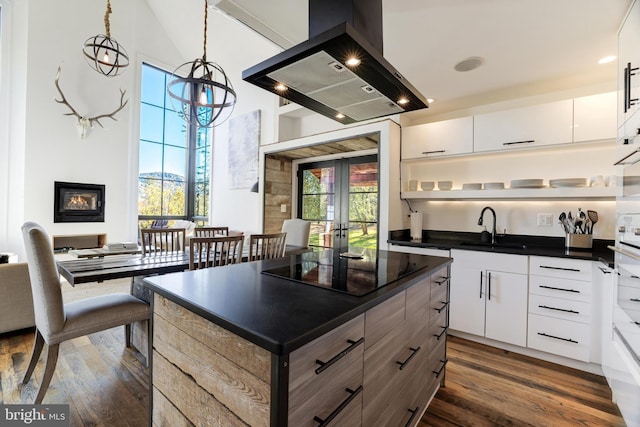 kitchen with a sink, dark countertops, island range hood, and white cabinets