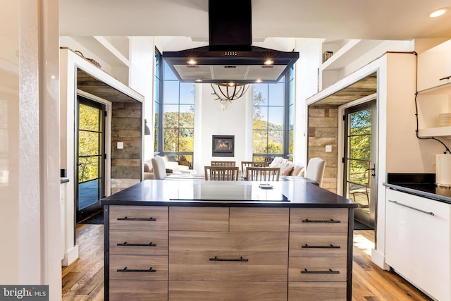 kitchen with dark countertops, open floor plan, light wood-style flooring, and island range hood