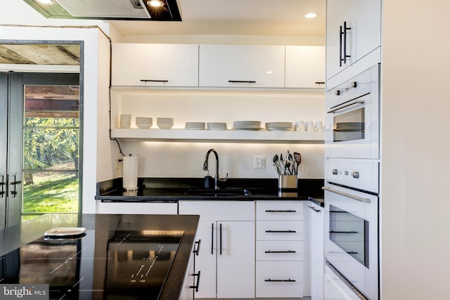 kitchen featuring dark countertops, black cooktop, white cabinetry, a sink, and recessed lighting