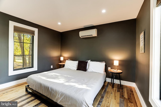 bedroom featuring recessed lighting, baseboards, wood finished floors, and a wall mounted air conditioner