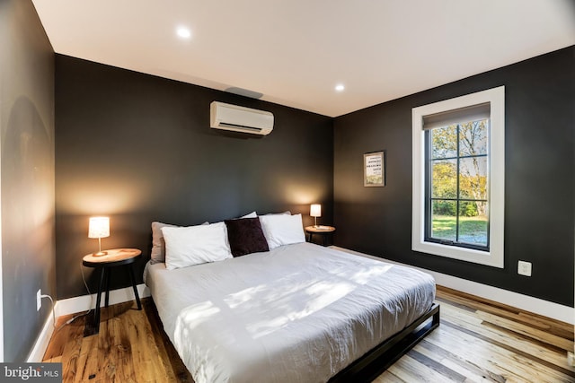 bedroom with recessed lighting, a wall mounted air conditioner, wood finished floors, and baseboards