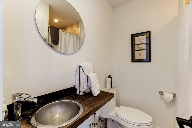 bathroom featuring curtained shower, a sink, and toilet