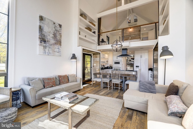 living area featuring plenty of natural light, a high ceiling, and dark wood-style flooring