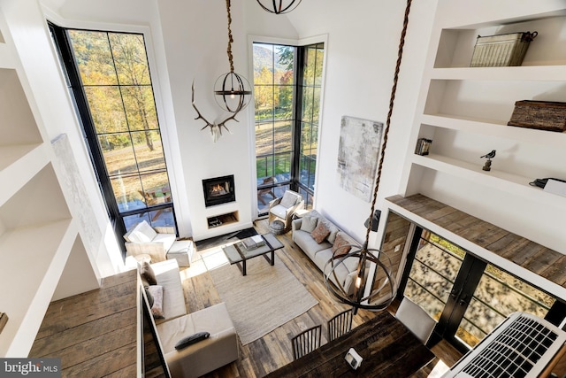 living room featuring built in shelves, a fireplace, and wood finished floors