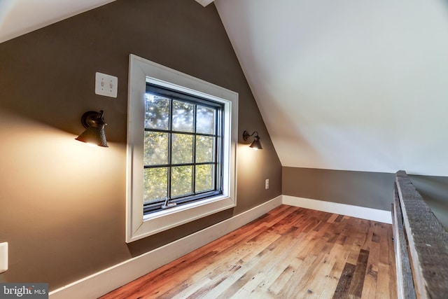 additional living space featuring lofted ceiling, wood finished floors, and baseboards