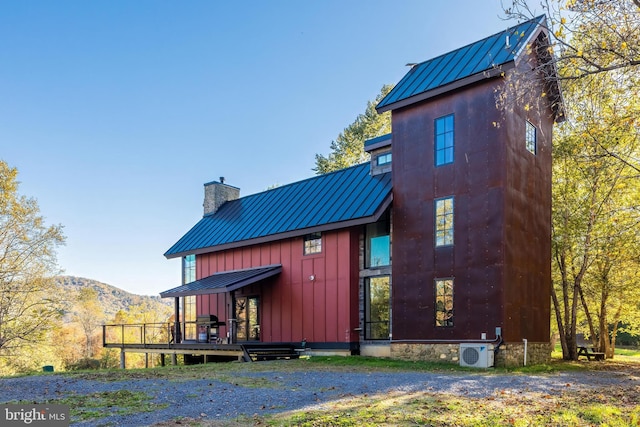 back of property with metal roof, ac unit, a mountain view, a standing seam roof, and a chimney