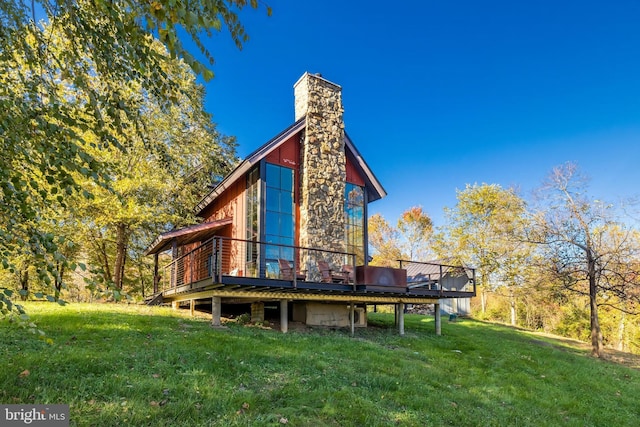 back of property with a lawn, a chimney, and a wooden deck