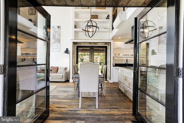 dining area with dark wood-style floors, french doors, a wall unit AC, and a notable chandelier