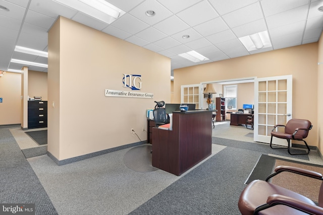 carpeted office space featuring french doors and a drop ceiling