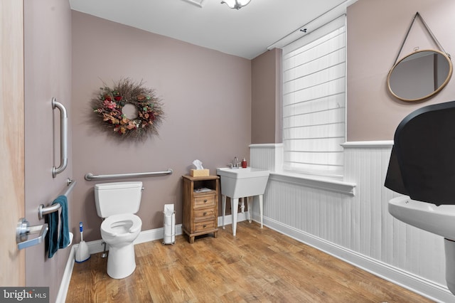 bathroom with toilet, wood-type flooring, and wooden walls