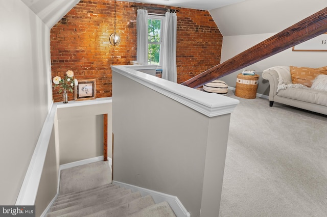 stairway featuring carpet flooring, lofted ceiling, and brick wall