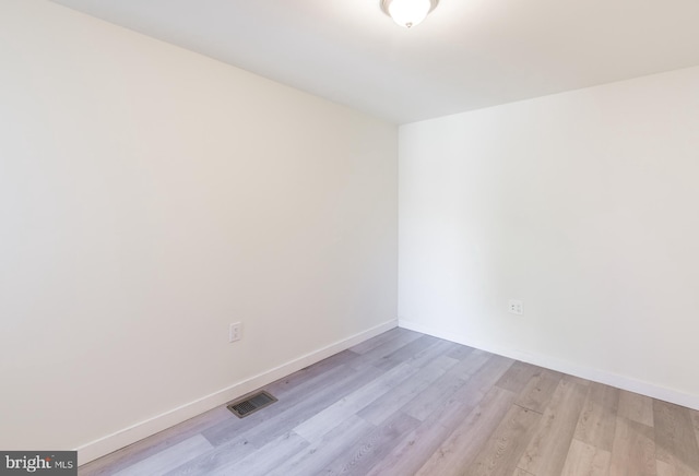empty room with light wood-style flooring, baseboards, and visible vents