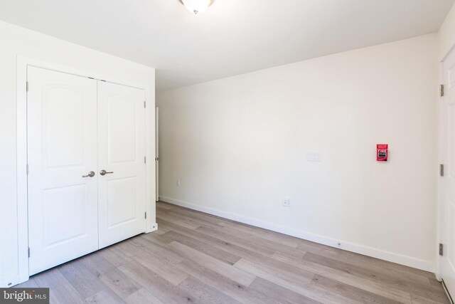 unfurnished bedroom with light wood finished floors, a closet, and baseboards