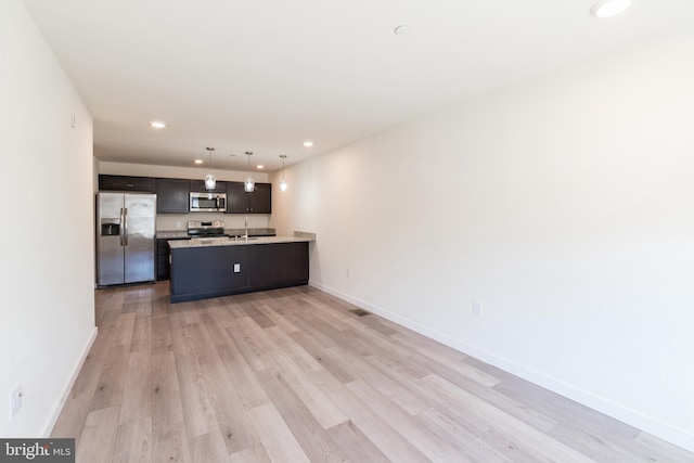 kitchen with a peninsula, a sink, light wood-type flooring, appliances with stainless steel finishes, and recessed lighting