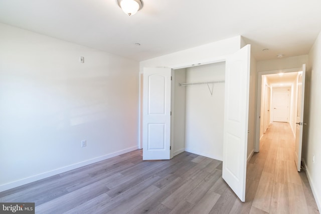 unfurnished bedroom with a closet, light wood-type flooring, and baseboards