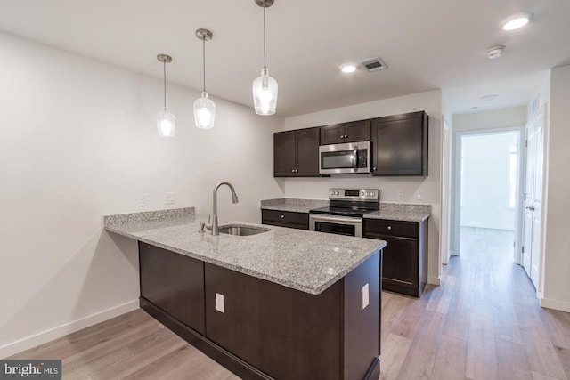 kitchen featuring pendant lighting, sink, kitchen peninsula, and appliances with stainless steel finishes