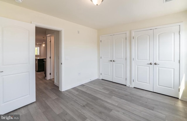 unfurnished bedroom featuring multiple closets and light hardwood / wood-style floors