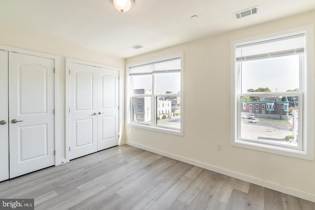 unfurnished bedroom featuring multiple closets and light wood-type flooring